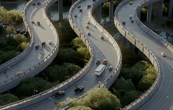 Curved elevated highway lanes with various vehicles driving above green trees and water.